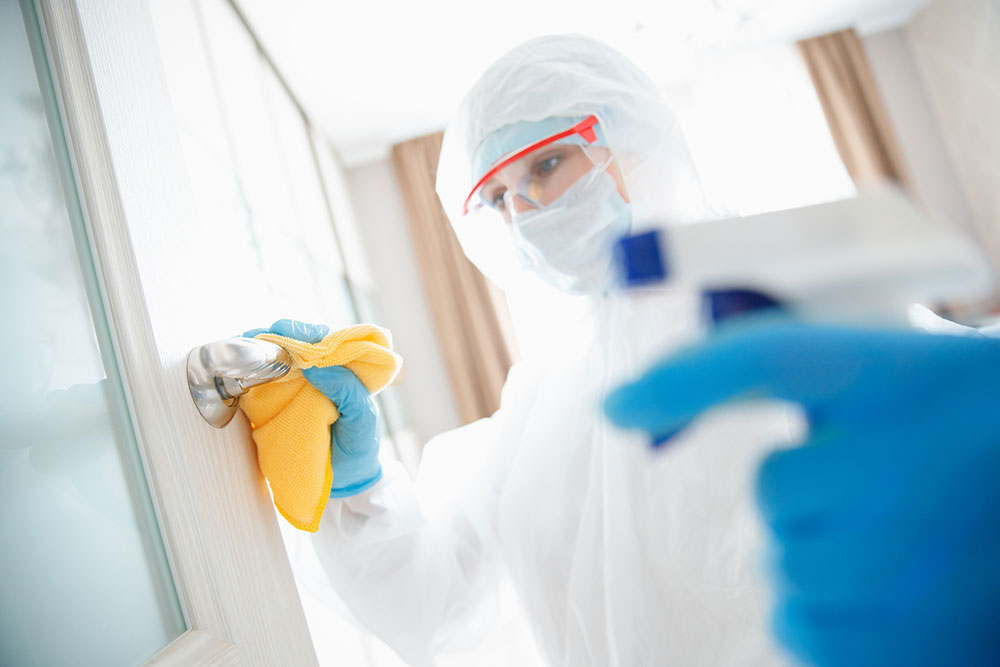 A person in a white protective suit doing disinfection services